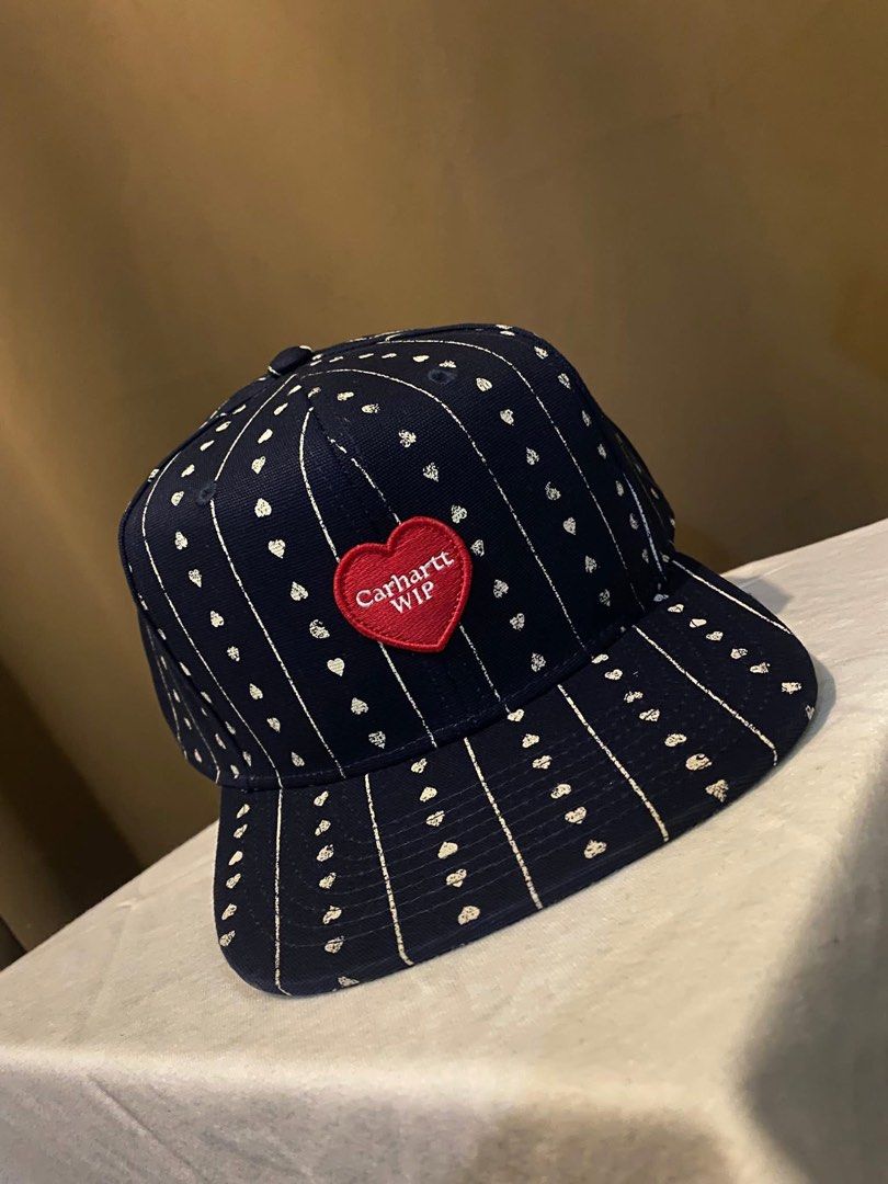 Carhartt WIP Navy Heart Pattern Snapback Cap (Category: Caps & Hats) located in Tarlac. Submitted by LStuff (Listing ID 1445434886, Image 2). Description: - Navy blue Carhartt WIP snapback cap - All-over white heart and pinstripe pattern - Red heart patch with white 'Carhartt WIP' logo on the front - Adjustable snapback closure at the back - Ideal for casual wear 3k.