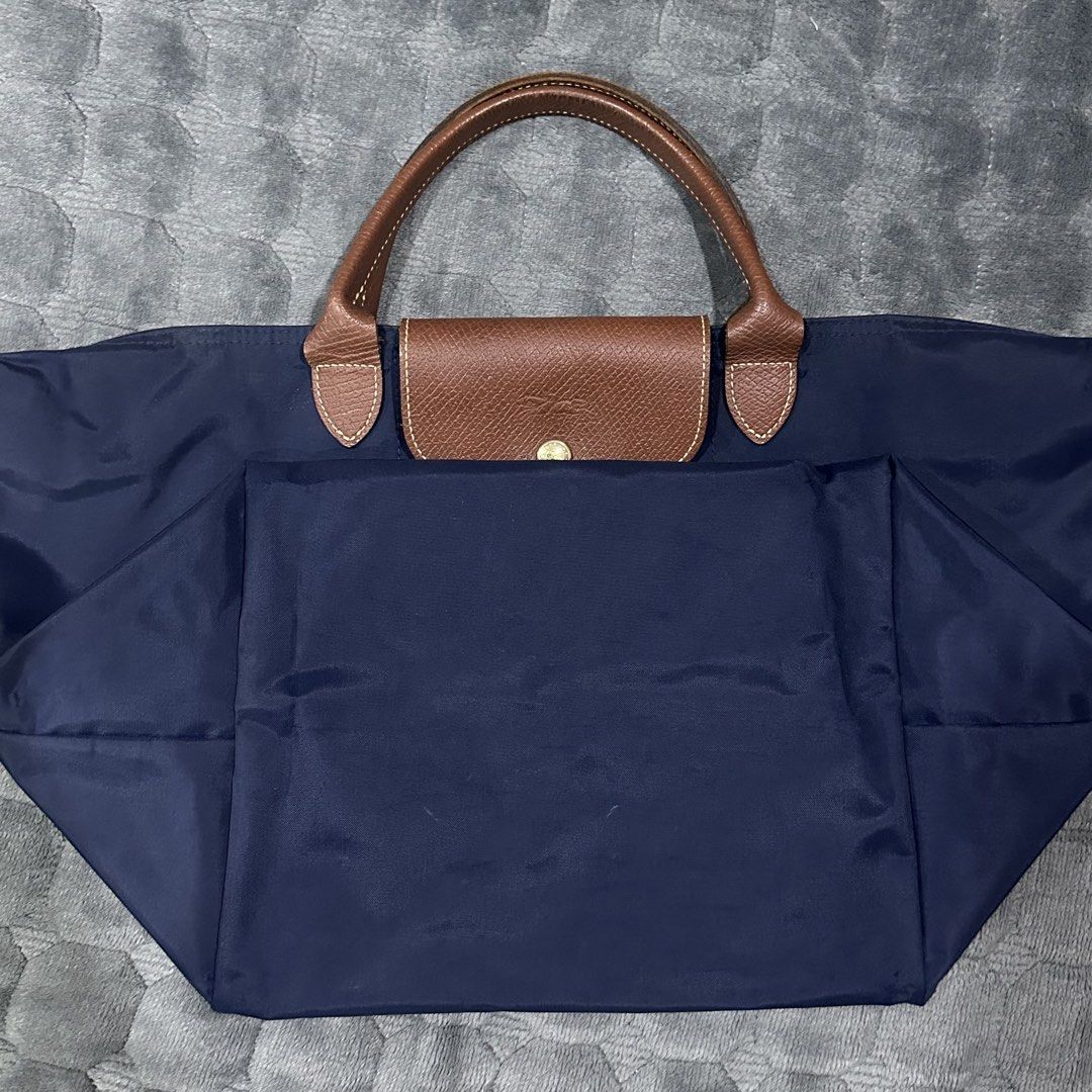 Longchamp Le Pliage Tote Bag Navy Blue (Category: Luxury Bags & Wallets) located in Quezon City. Submitted by gamarika (Listing ID 1445520395, Image 3). Description: - Classic navy blue Longchamp tote - Durable nylon body with leather handles and trim - Spacious interior with zip closure - Folds down for easy storage - Ideal for everyday use or travel - Versatile and long-lasting -sewn sides.