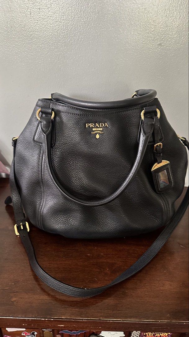 Prada Black Leather Tote Bag (Category: Luxury Bags & Wallets) located in Makati City. Submitted by janeabat (Listing ID 1445493508, Image 2). Description: Prelove Authentic Prada bag - Black pebbled leather - Gold hardware details - Top handles - Detachable shoulder strap - Includes leather luggage tag - Spacious interior - Ideal for daily use or travel - Classic Prada piece.