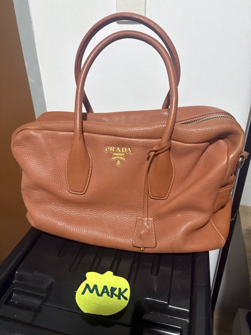 Prada Brown Leather Satchel Handbag (Category: Luxury Bags & Wallets) located in Cebu City. Submitted by xoxoxo888marco (Listing ID 1445602459, Image 1). Description: - Authentic Prada satchel in brown pebbled leather. - Elegant gold hardware details. - Comfortable top handles for easy carrying. - Secure zip closure. - Includes original leather tag. - Minor wear on corners and hardware, adding character. - Ideal as a stylish everyday bag..