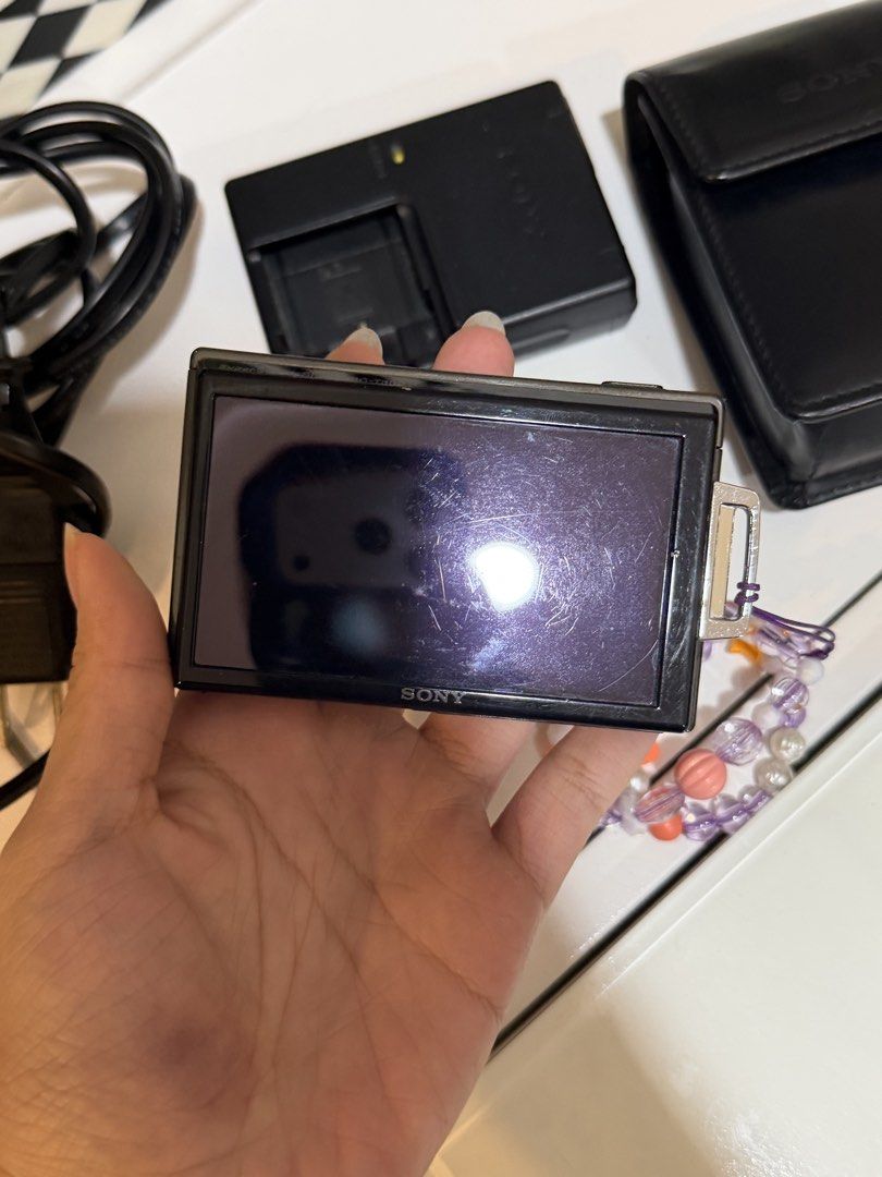 Sony Digital Camera Charger, Case, and Strap (Category: Cameras) located in Makati City. Submitted by _saleph_ (Listing ID 1445580862, Image 2). Description: - Genuine Sony digital camera charger with power cord - Original Sony black leather camera case - Adorable beaded strap with purple, pink, and orange beads - All items are Sony branded - Ideal accessory for your Sony camera.