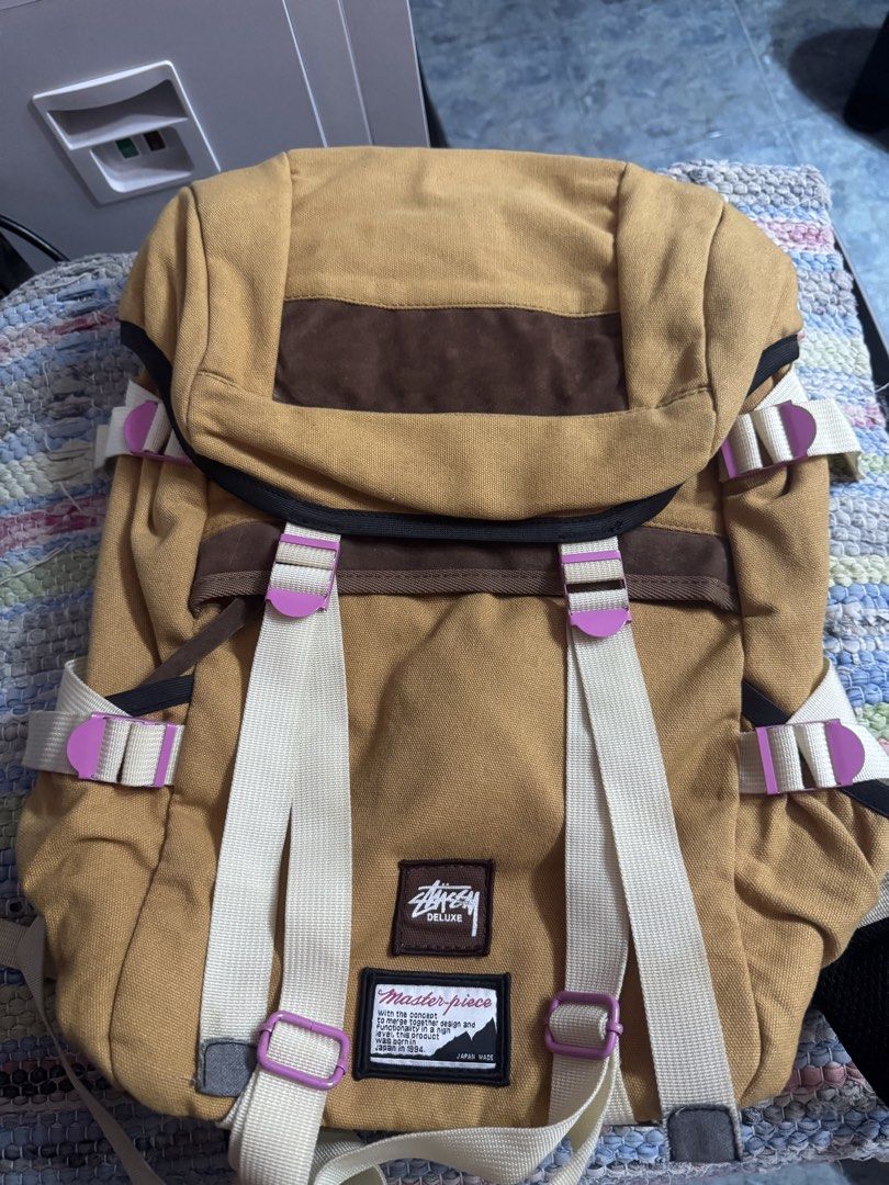 Stussy x Deluxe Master-piece Backpack Tan (Category: Backpacks) located in Makati City. Submitted by vinsanity41546 (Listing ID 1445587409, Image 1). Description: - Tan canvas backpack - Brown suede accents - Stussy Deluxe x Master-piece collaboration - Adjustable straps with purple buckles - Side zip pocket - Ideal for everyday use or travel.