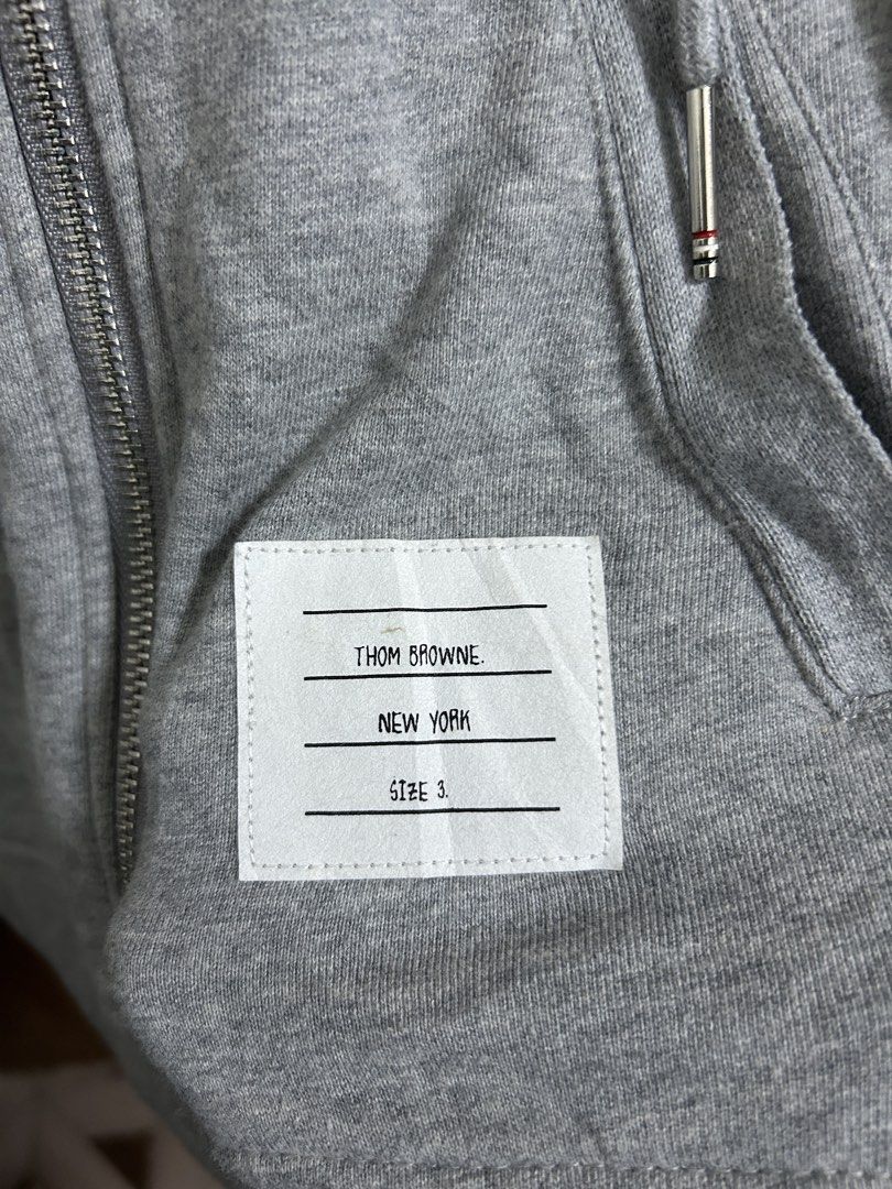 Thom Browne Grey Zip-Up Hoodie Size 3 (Category: Coats, Jackets and Outerwear) located in Manila. Submitted by andotputla37237 (Listing ID 1445555445, Image 3). Description: - Grey zip-up hoodie from Thom Browne - Signature four-stripe detail on the sleeve - Made in Japan - Size 3 - Good quality, substantial material - Perfect for casual wear.