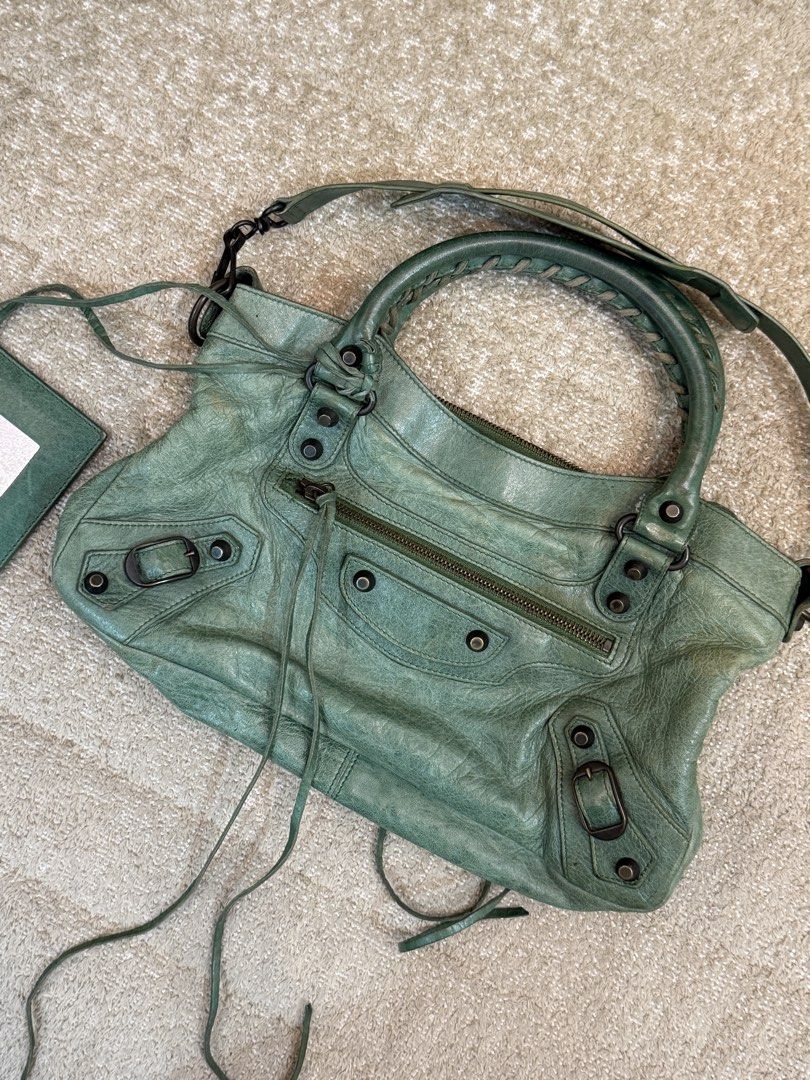 Balenciaga First Green (Category: Luxury Bags & Wallets) located in Manila. Submitted by shopelisse (Listing ID 1445740026, Image 2). Description: - Authentic Green Balenciaga City Bag - Made from soft, genuine leather - Dual top handles - Detachable shoulder strap for versatile carrying - Signature mirror tag included - Secure top zipper closure - Interior lined with black fabric - Please note: Shows some signs of wear on the leather and hardwar