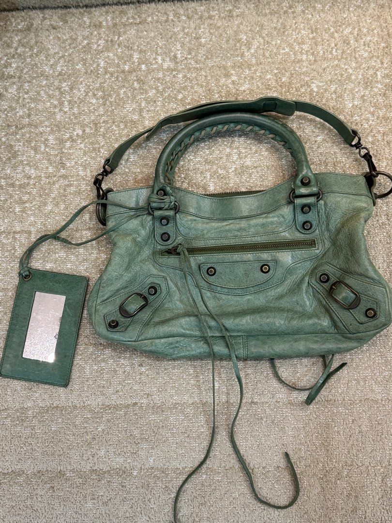 Balenciaga First Green (Category: Luxury Bags & Wallets) located in Manila. Submitted by shopelisse (Listing ID 1445740026, Image 1). Description: - Authentic Green Balenciaga City Bag - Made from soft, genuine leather - Dual top handles - Detachable shoulder strap for versatile carrying - Signature mirror tag included - Secure top zipper closure - Interior lined with black fabric - Please note: Shows some signs of wear on the leather and hardwar