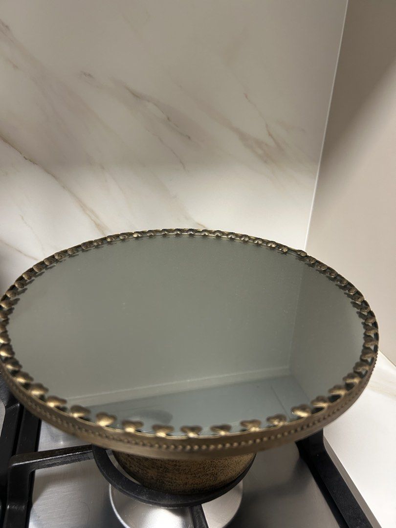 Cake Stand (Category: Bakeware) located in Singapore. Submitted by the.petite.wardrobe (Listing ID 1445760721, Image 2). Description: - Ornate gold-trimmed cake stand - Mirrored top surface - Vintage distressed gold base finish - Ideal for displaying cakes, desserts, or as a decorative centerpiece - Beautiful light reflection from mirrored surface - Dimensions: diameter (25.5cm), height (13.5cm), base stand diameter (12.5cm) - Suitable for partie