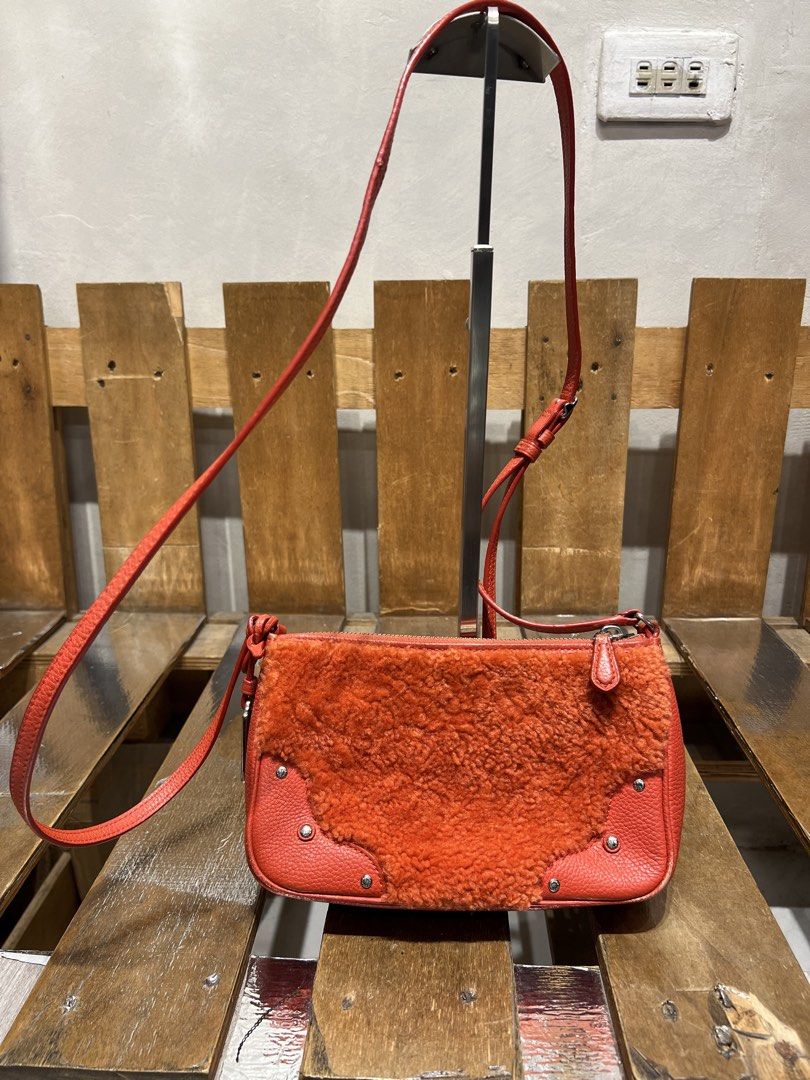 Coach Orange Leather & Shearling Crossbody Bag (Category: Cross-body Bags) located in Manila. Submitted by -handpick- (Listing ID 1445751299, Image 2). Description: Orange leather crossbody bag with fluffy shearling front detail. Silver hardware and zip closure. Adjustable strap. Coach New York tag visible. Small and compact, great for essentials. Perfect for adding a pop of color to any outfit. Issue : Cracks on leather Material (Sign of wear in