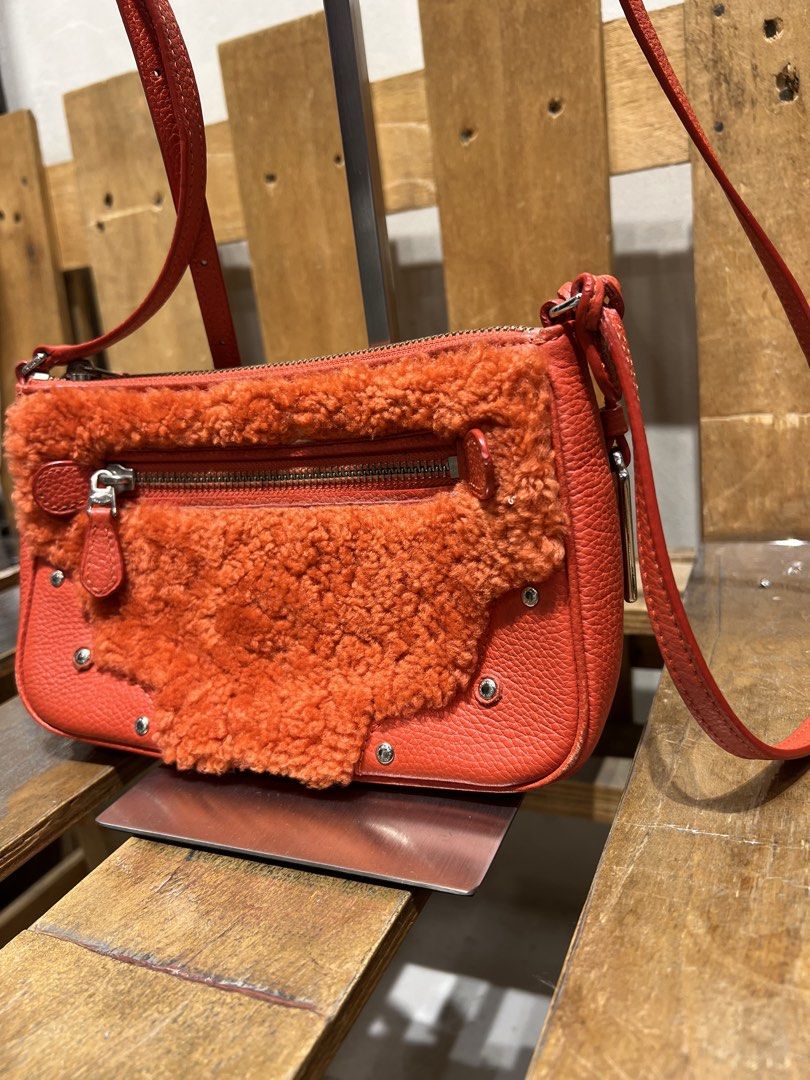 Coach Orange Leather & Shearling Crossbody Bag (Category: Cross-body Bags) located in Manila. Submitted by -handpick- (Listing ID 1445751299, Image 3). Description: Orange leather crossbody bag with fluffy shearling front detail. Silver hardware and zip closure. Adjustable strap. Coach New York tag visible. Small and compact, great for essentials. Perfect for adding a pop of color to any outfit. Issue : Cracks on leather Material (Sign of wear in