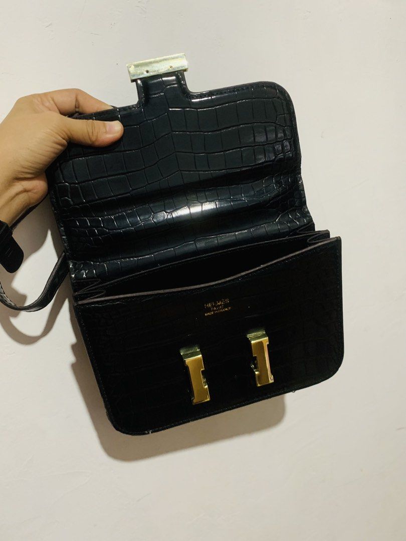 HERMES Constance (Category: Luxury Bags & Wallets) located in Malaybalay. Submitted by yanshoppe (Listing ID 1445659219, Image 2). Description: - Elegant black crocodile embossed handbag - Features a stylish gold 'H' clasp closure - Includes a thin shoulder strap for easy carrying - Interior boasts a main compartment and smaller pockets - Clean interior, ready for use - Ideal for evening events or elevating any outfit - Approximate measurements: 