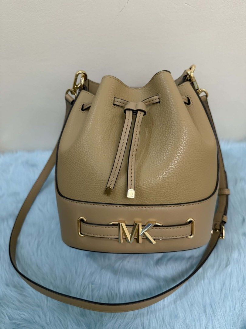 Michael Kors Beige Leather Bucket Bag (Category: Luxury Bags & Wallets) located in Manila. Submitted by mommynikaden (Listing ID 1445744880, Image 1). Description: - Brand: Michael Kors - Color: Beige - Material: Leather - Style: Bucket Bag - Closure: Drawstring top - Hardware: Gold tone MK logo on front strap - Strap: Long, adjustable shoulder strap - Ideal for: Everyday use.