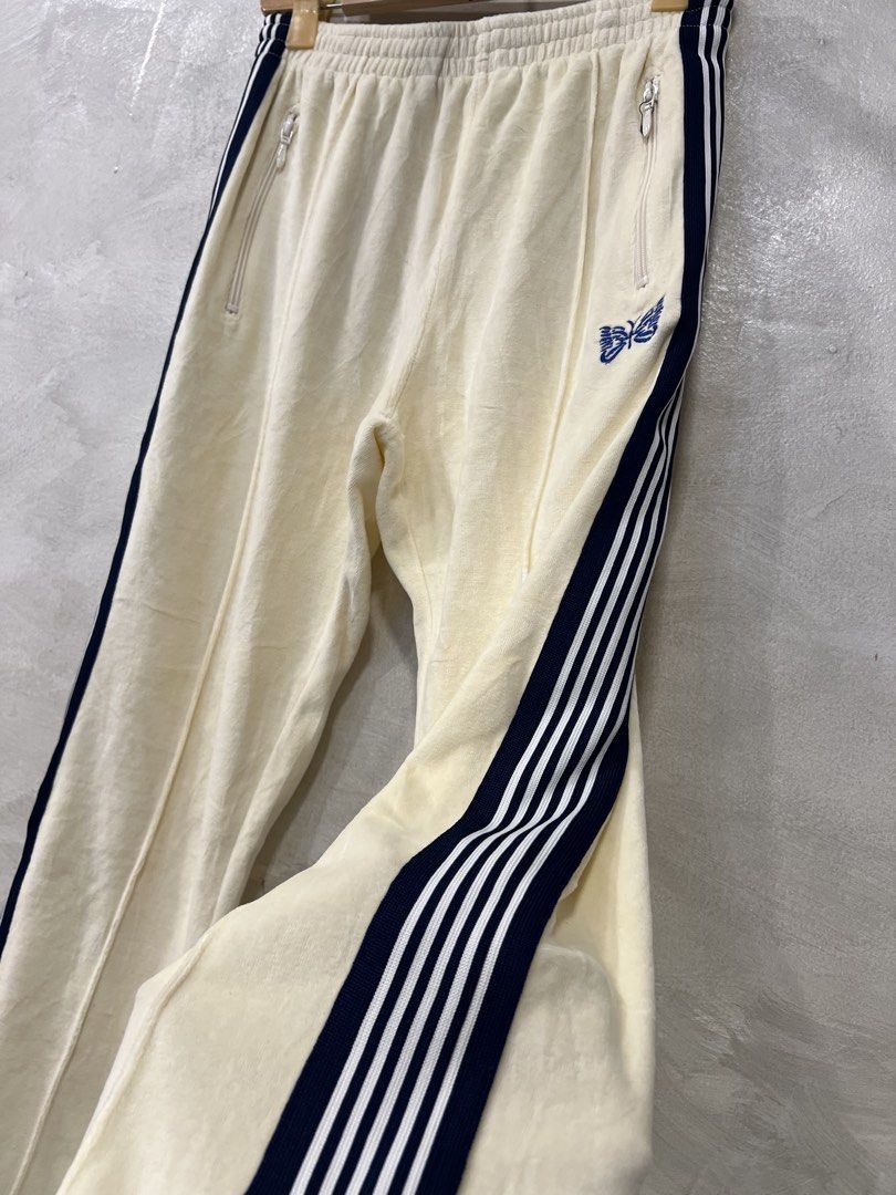 Needles Velour Narrow Track Pants (Category: Joggers) located in Manila. Submitted by -handpick- (Listing ID 1445750865, Image 3). Description: Cream velour track pants from Needles. Navy blue stripes down the sides. Embroidered butterfly logo on the left leg. Zipper pockets on both sides and one on the back. Elastic waistband with drawstring. Velour material feels soft. Great for casual wear. Size : Small on tag Dimensions : Length : 35.5 Inseam