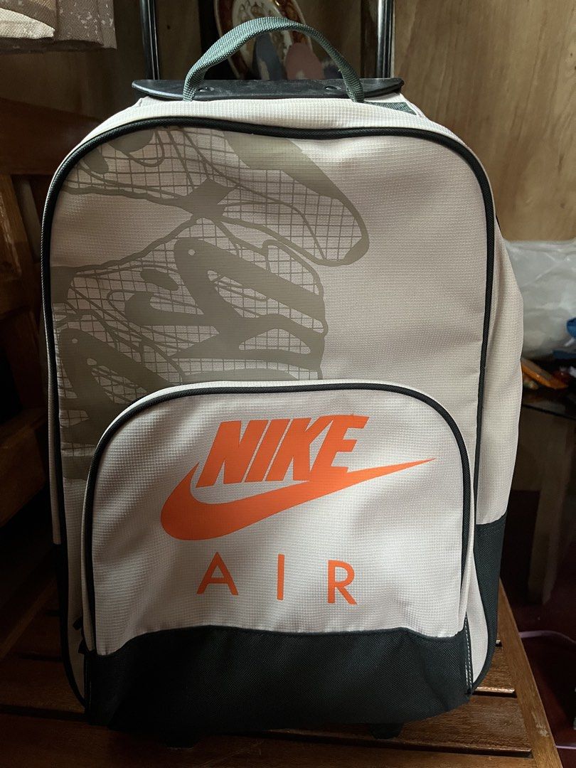 Nike Air Rolling Backpack Luggage Bag (Category: Backpacks) located in Tandag. Submitted by maryarlale42144 (Listing ID 1445787769, Image 2). Description: - Nike Air rolling backpack - Color: Light grey with orange Nike Air logo - Accents: Black - Features: Retractable handle and wheels - Material: Polyester - Ideal for: Travel or school - Condition: Some scuffing on the handle pole.