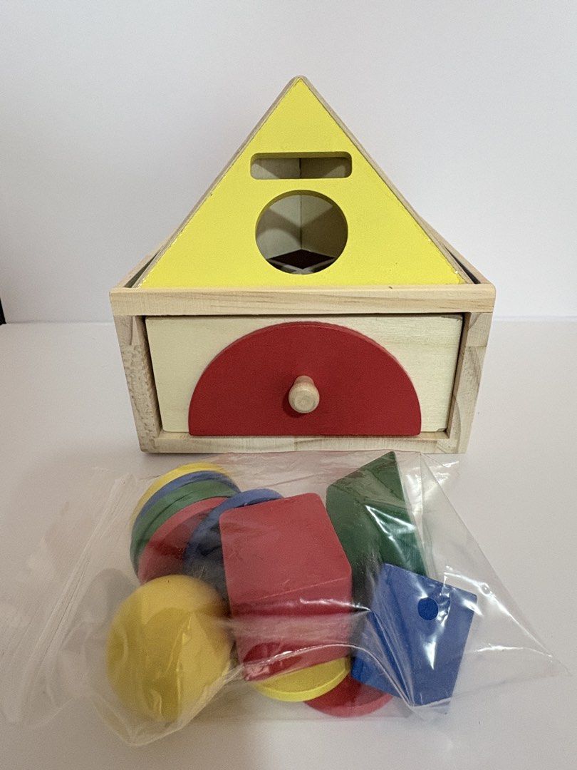 Shape sorting (Category: Infant Playtime) located in Singapore. Submitted by happycongstore (Listing ID 1445697655, Image 4). Description: - Educational shape recognition and sorting toy for children aged 3+. - Helps children learn shapes and colors through interactive play. - Set includes a wooden sorting box with various shaped holes. - Comes with colorful wooden blocks: red circle, red square, green circle, green trapezoid, blue circle, blue t