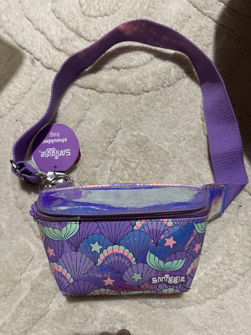 Smiggle Purple Mermaid Shell Shoulder Bag (Category: Shoulder Bags) located in Cabatuan. Submitted by desrceio (Listing ID 1445627389, Image 1). Description: Cute purple Smiggle shoulder bag with mermaid shell design and iridescent finish. Adjustable strap. Brand new with tags. Perfect for kids or fun accessory lovers!.