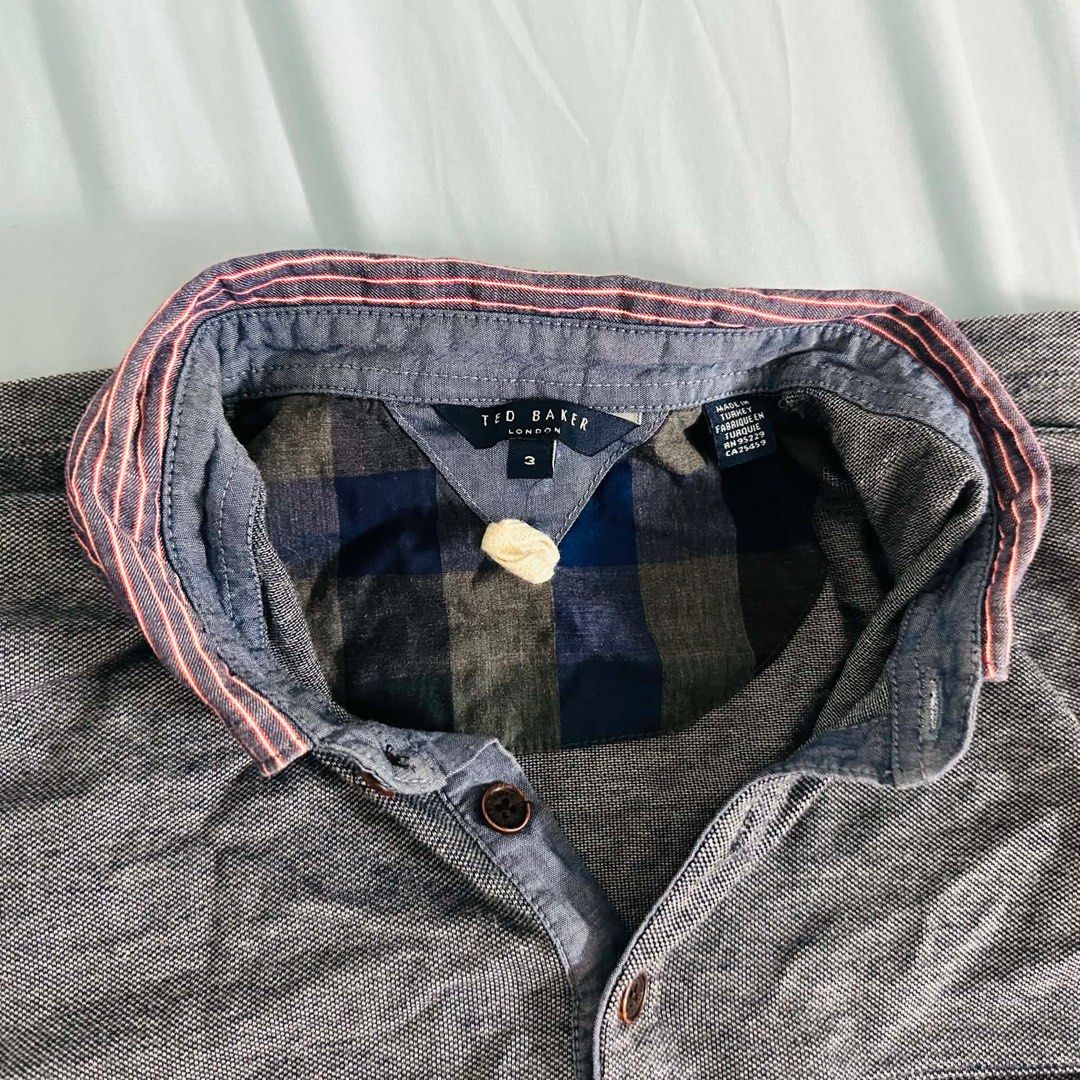 Ted Baker London Grey Button-Up Shirt (Category: Tshirts & Polo Shirts ) located in Makati City. Submitted by sweetdeclutter (Listing ID 1445647586, Image 1). Description: - Brand: Ted Baker London - Color: Grey - Style: Button-up shirt - Size: Approximately Size 2 - Inner Lining: Blue and grey checkered pattern - Collar Detail: Subtle pink stripe - Buttons: Dark brown.