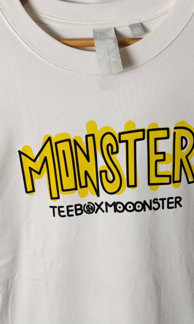 TeeBox (Category: Tshirts & Polo Shirts ) located in Rizal. Submitted by itsmecle0 (Listing ID 1445729624, Image 3). Description: The item highlighted is a TEEBOX Monster Graphic T-Shirt, showcasing a street-art inspired cartoon monster print. Key Visual Details Graphic Design: It features a vibrant turquoise three-eyed cartoon dinosaur or monster with orange scales, a bold black-and-white "TEEBOX" logo stamped across its mouth, and stylized "MIN