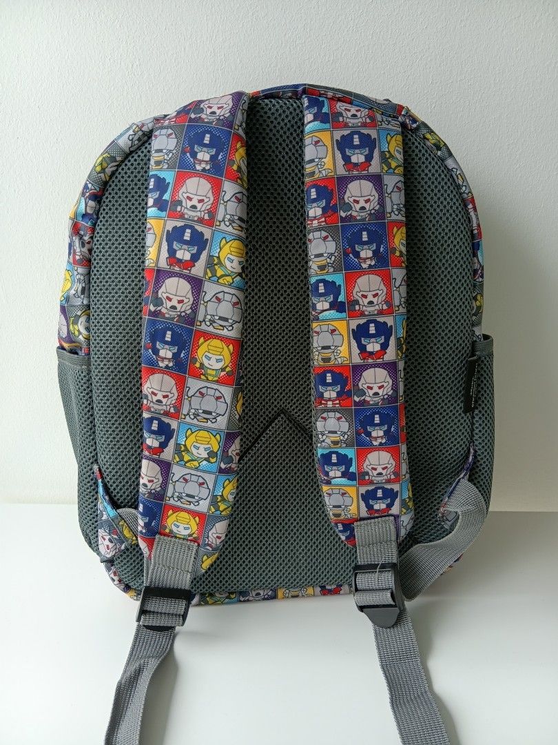 Transformers Chibi Comic Strip Grid Pattern School Backpack (Category: Babies & Kids Fashion) located in Singapore. Submitted by pretty.petite (Listing ID 1444707146, Image 3). Description: - Original price $45. - Colourful multi-paneled comic grid pattern featuring chibi-style character faces of classic Transformers like Optimus Prime, Bumblebee, and Megatron. - Adorned with a prominent raised rubber Autobots shield patch on the top centre. - Fe