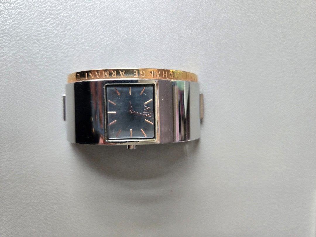 AX Armani Exchange Two-Tone Cuff Watch (Category: Luxury Watches) located in Quezon City. Submitted by mgdeclutters (Listing ID 1445851049, Image 2). Description: Selling an AX Armani Exchange watch. It has a silver and rose gold cuff design. The watch face is black with silver hands and markers. The band is made of metal links. The AX logo is visible on the watch face and the clasp. This is a stylish accessory. It's a cuff style watch, easy to w
