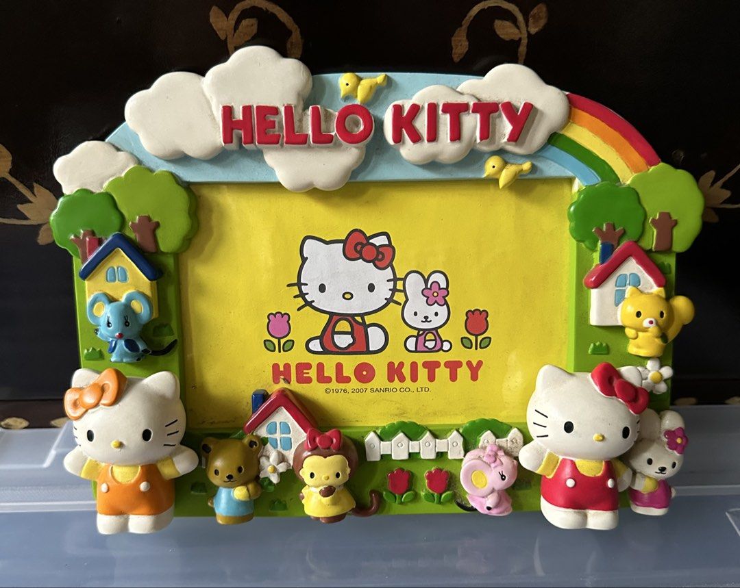 Hello Kitty Photo Frame with Figures and Rainbow (Category: Frames & Pictures) located in Quezon City. Submitted by mitchapple88 (Listing ID 1445851132, Image 1). Description: - Adorable Kitty photo frame featuring Kitty, Mimmy, and other Sanrio characters (mouse, bear, monkey). - Adorned with a rainbow and clouds at the top. - Vibrant bright yellow background. - Ideal for showcasing a cherished photograph. - Copyright 1976, 2007 Sanrio Co., Ltd.