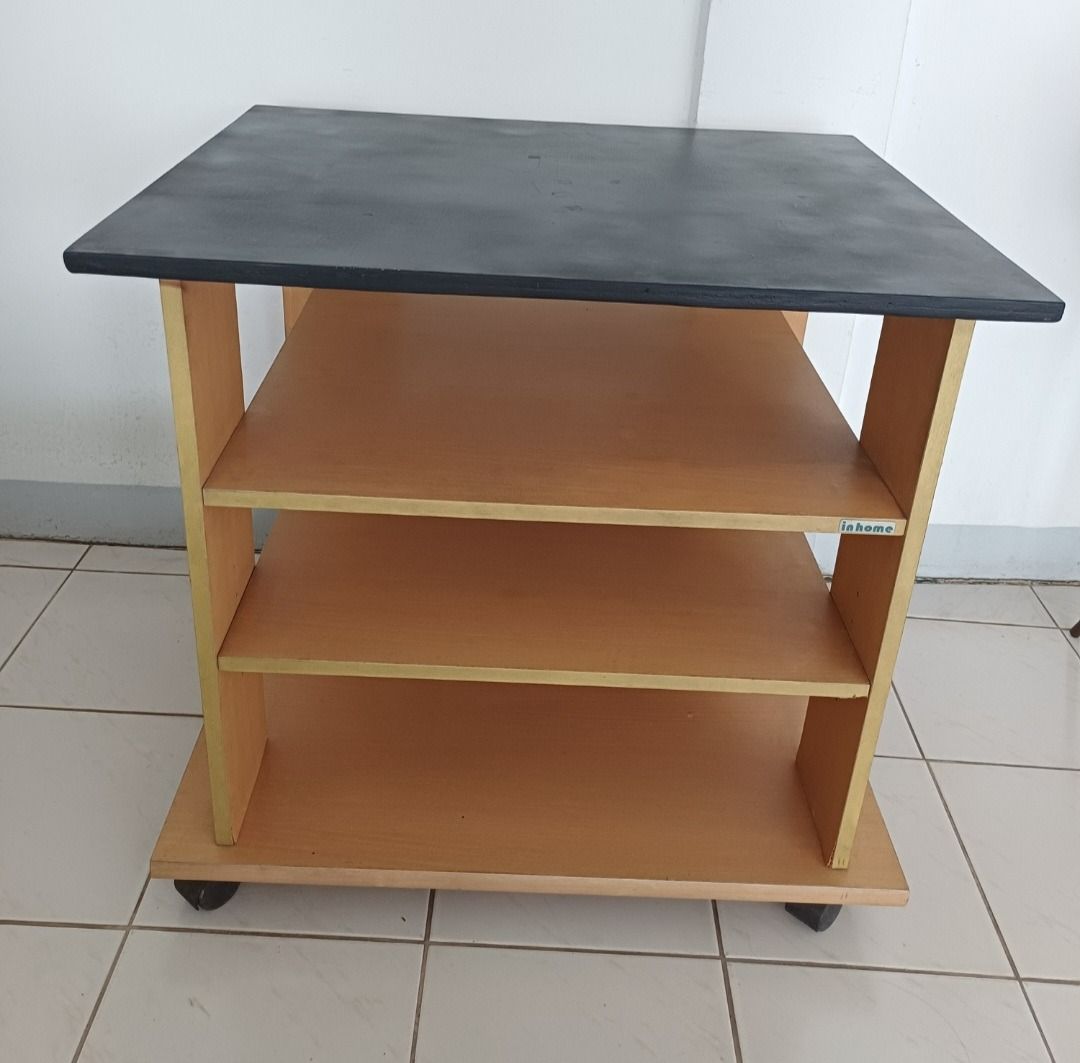 In Home Wooden Utility Cart with Wheels (Category: Shelves, Cabinets & Racks) located in Quezon City. Submitted by CraftsItemsCleanUpSale (Listing ID 1445913021, Image 1). Description: [Decluttering Sale] In Home Wooden Utility Cart with Wheels Dimensions: L29.5 x W23.5 x H28 inches Features: Wooden shelf unit with a black top. It has three shelves and sits on wheels for easy movement. The wood has a light brown finish. Great for storage or displ