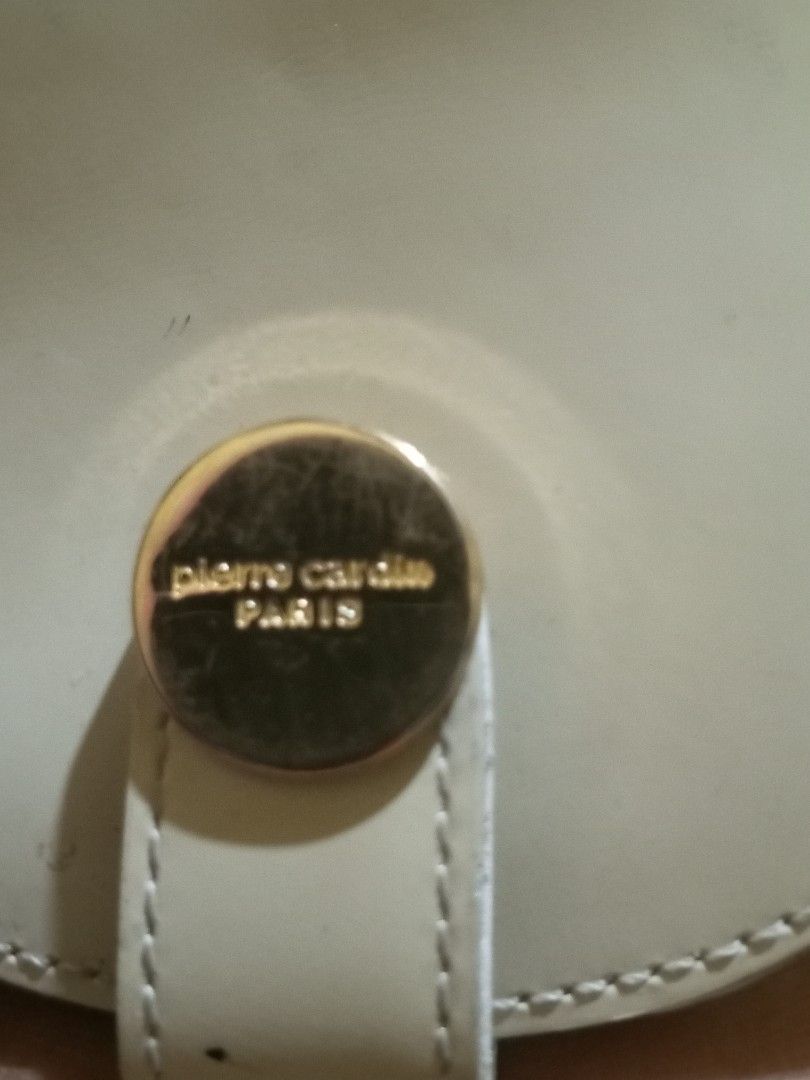 Pierre Cardin Paris Coin Pouch (Category: Purses & Pouches) located in Magalang. Submitted by zeiansoria64090 (Listing ID 1445800048, Image 3). Description: - Cream colored coin pouch from Pierre Cardin Paris - Features a gold button closure - Interior is black - Shows some signs of wear on exterior and interior, particularly on the white flap - Still functional for holding coins or small essentials.