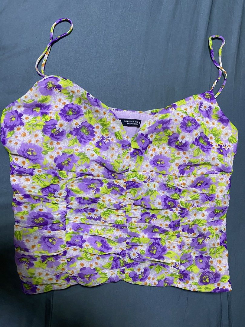 Zara Floral Ruched Camisole Top (Category: Sleeveless) located in Quezon City. Submitted by esmnl (Listing ID 1445907267, Image 1). Description: - Cute purple and green floral camisole from Zara - Features a ruched front detail - Thin spaghetti straps - Lightweight fabric, ideal for warm weather - Versatile for dressing up or down - Size: Medium (M).