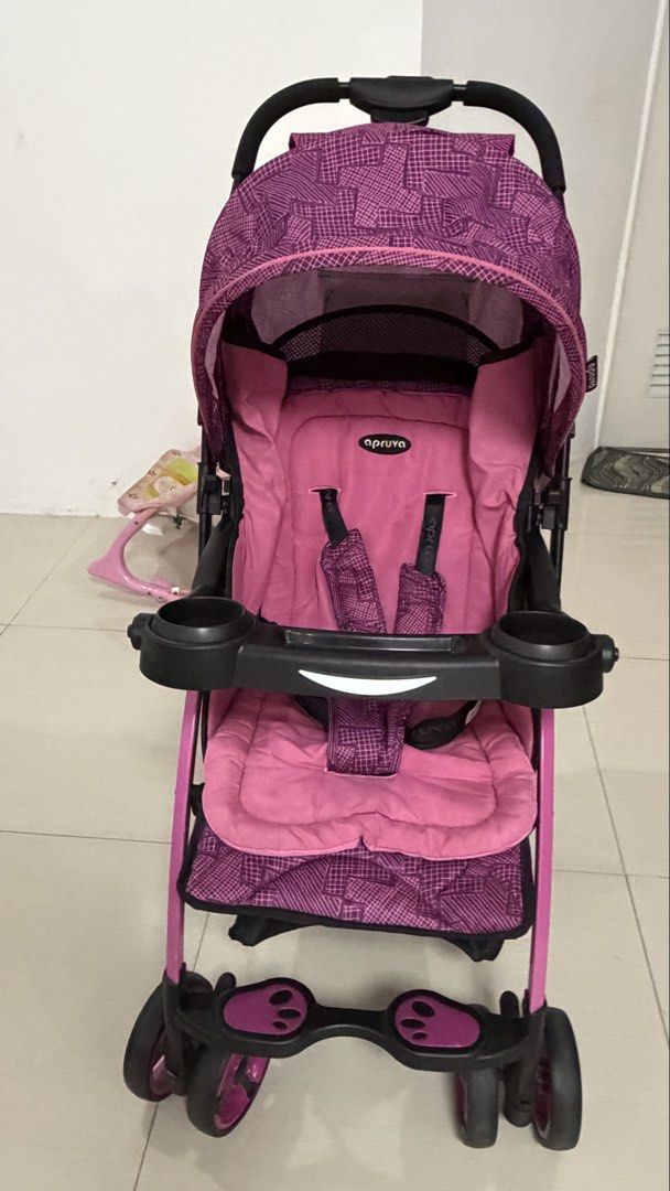 Apruva Stroller - Pink/Purple Geometric Pattern (Category: Strollers) located in Teresa. Submitted by bestfinds4u (Listing ID 1446073123, Image 2). Description: - Fun pink and purple geometric print - Canopy for sun protection - Tray with cup holders - Convenient storage basket underneath - Secure harness for safety - Easy to maneuver with swivel wheels - Ideal for walks and outings - FREE cotton cushion for comfort.