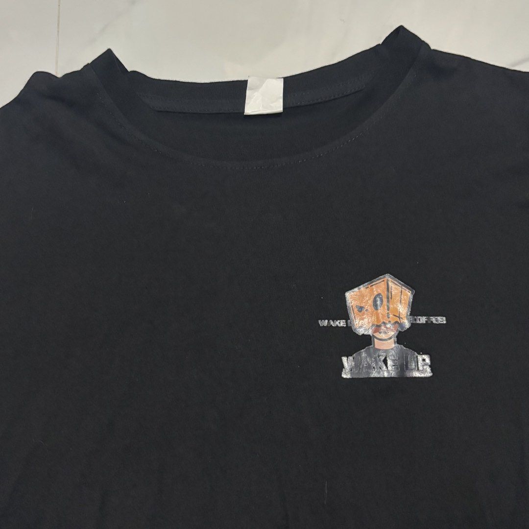 Black Graphic T-shirt with Box Head Design (Category: Tshirts & Polo Shirts ) located in Zaragoza. Submitted by starzoneph (Listing ID 1446098821, Image 2). Description: - Black t-shirt - Features a unique graphic of a person with a box on their head - Text reads 'WAKE UP AND SMELL THE COFFEE' - Comfortable and ideal for everyday casual wear Measurements 📏 Length: 24.5 Inches Width: 17 Inches.