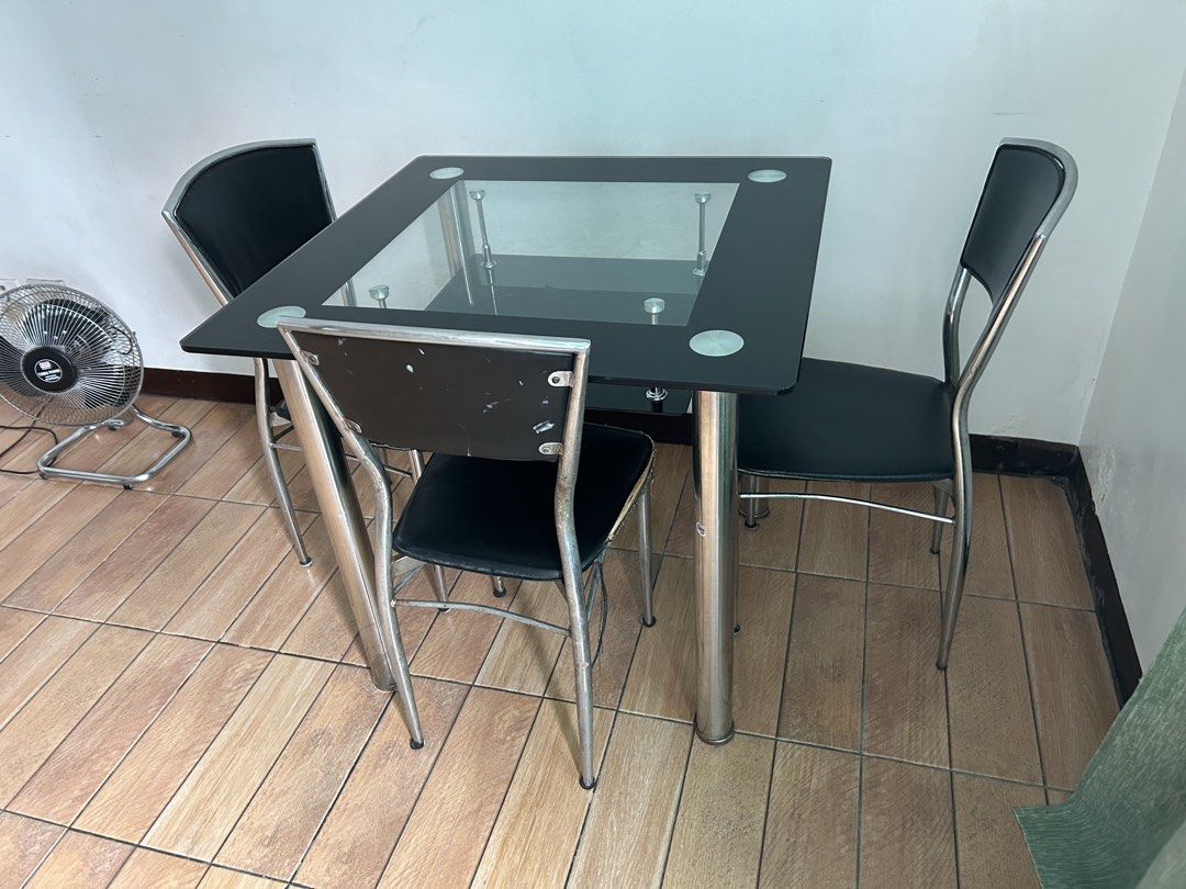 Glass Top Dining Table with 4 Black Chairs (Category: Tables & Sets) located in Quezon City. Submitted by calmrabbit_ffa1db (Listing ID 1446064142, Image 1). Description: - Square glass top dining table(tempered) - Black metal frame - Includes 4 black chairs with metal legs - Ideal for small dining areas - Minor scuffs on the back of the chairs - Table is sturdy and stable - Chairs are comfortable for seating(need re upholster) - Ready for its ne