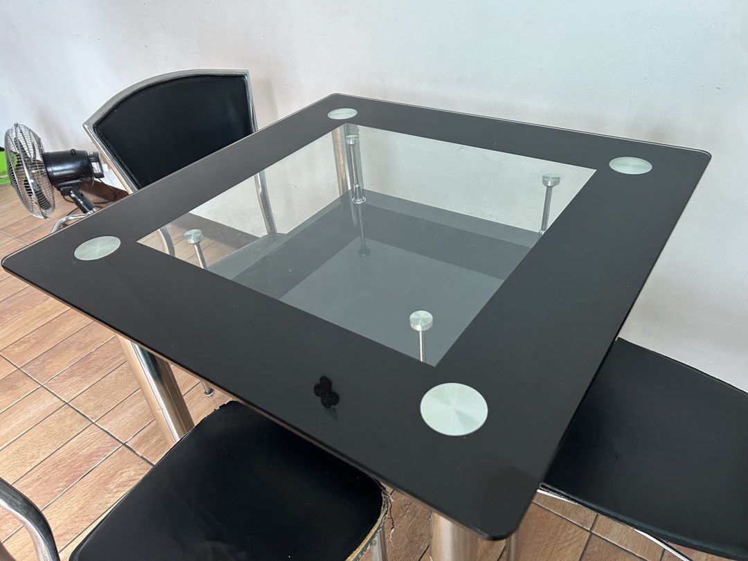Glass Top Dining Table with 4 Black Chairs (Category: Tables & Sets) located in Quezon City. Submitted by calmrabbit_ffa1db (Listing ID 1446064142, Image 3). Description: - Square glass top dining table(tempered) - Black metal frame - Includes 4 black chairs with metal legs - Ideal for small dining areas - Minor scuffs on the back of the chairs - Table is sturdy and stable - Chairs are comfortable for seating(need re upholster) - Ready for its ne