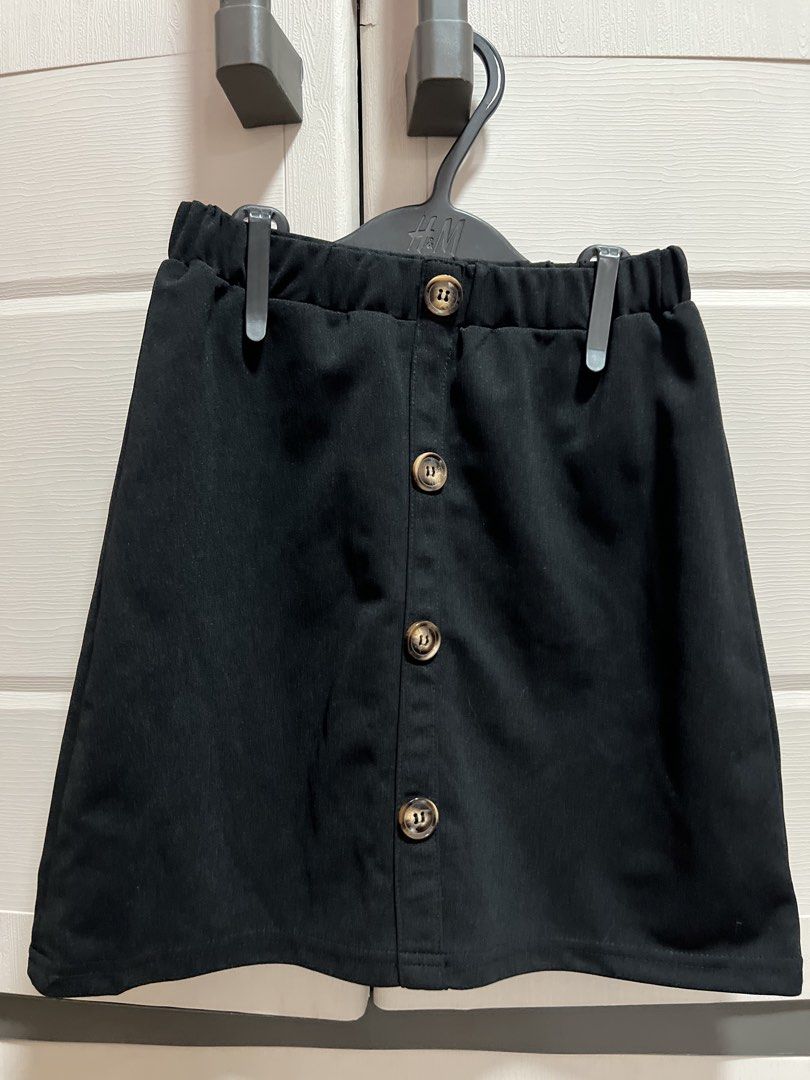 SHEIN Black Button-Front Skirt 11-12Y (Category: Babies & Kids Fashion) located in Cainta. Submitted by p3spreloved (Listing ID 1445999169, Image 1). Description: - Black A-line skirt from SHEIN - Comfortable elastic waistband - Stylish button-front detail - Versatile for casual or dressed-up outfits - Easy to pair with various tops - Size: 11-12 Years Length 15in Waist when laid flat 11in but still stretchable upto 14in so it fits 28in waist.