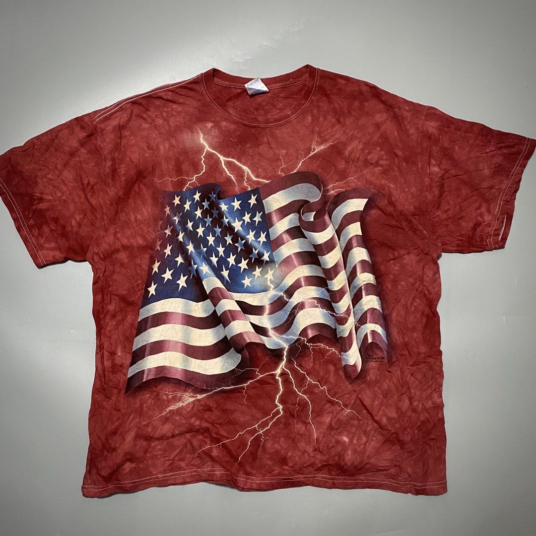 Vintage The Mountain USA Flag Lightning (Category: Tshirts & Polo Shirts ) located in Imus. Submitted by fndsvntg_307 (Listing ID 1446022560, Image 1). Description: - The Mountain 2011 - Size: XL - Design: American flag with lightning - Effect: Red tie-dye - Material: Gildan Heavy Cotton - Occasion: Patriotic events, bold casual wear.