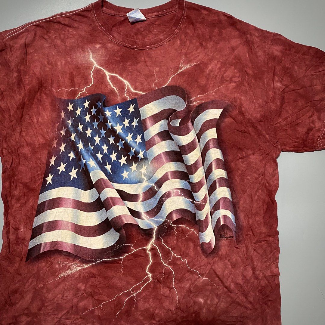 Vintage The Mountain USA Flag Lightning (Category: Tshirts & Polo Shirts ) located in Imus. Submitted by fndsvntg_307 (Listing ID 1446022560, Image 2). Description: - The Mountain 2011 - Size: XL - Design: American flag with lightning - Effect: Red tie-dye - Material: Gildan Heavy Cotton - Occasion: Patriotic events, bold casual wear.