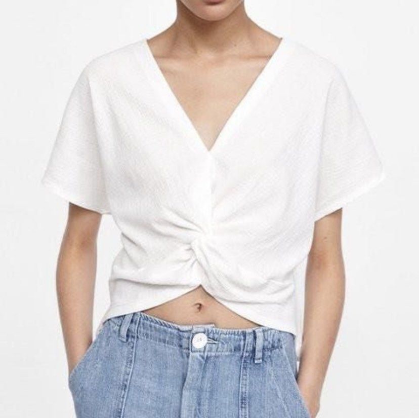Zara White Twisted V-Neck Short Sleeve Top (Category: Blouses) located in Batangas. Submitted by chicago2022 (Listing ID 1446014176, Image 1). Description: Chic white V-neck top with a front knot detail and flutter sleeves. Textured, cropped style perfect with high-waisted bottoms..