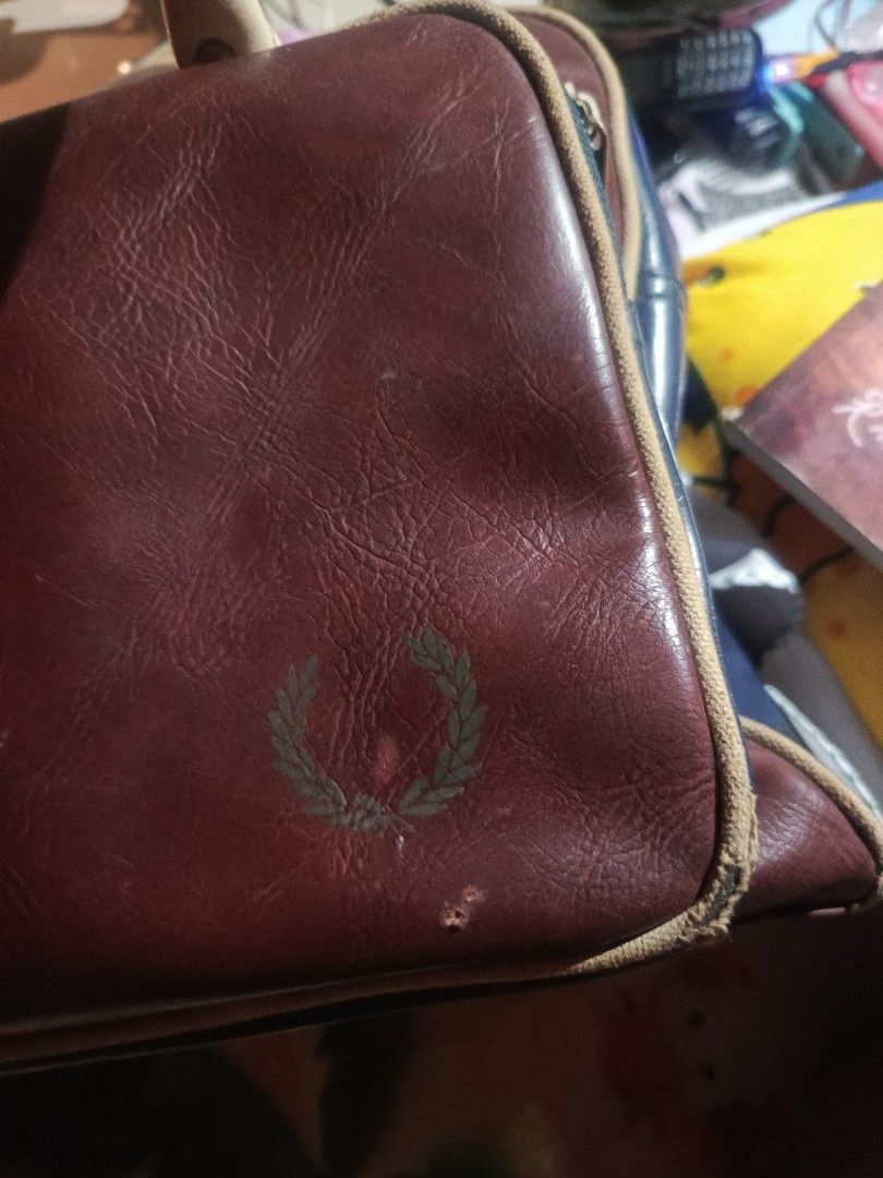 Authentic Vintage Fred Perry Barrel Bag (No Sling) (Category: Briefcases) located in Aparri. Submitted by jackdeclutter1111 (Listing ID 1446269248, Image 2). Description: Authentic Vintage Fred Perry Grip / Barrel Bag Color: Maroon / Navy Blue details Condition: Heavily used. Has visible surface scuffs/scratches due to age. No rips or deep tears. Issue: No more long shoulder sling strap included. Main hand straps are sturdy. Selling as-is. Perfec