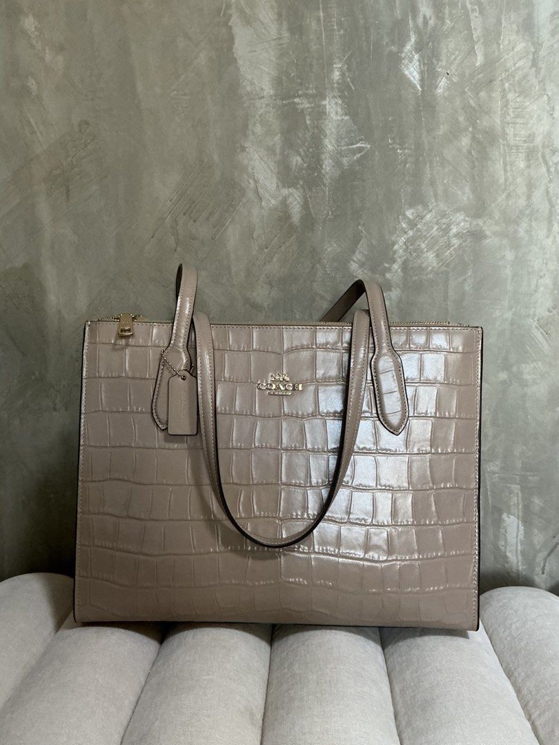Coach Nina Tote Bag (Category: Luxury Bags & Wallets) located in Bulacan. Submitted by slvvvxx (Listing ID 1446251669, Image 1). Description: Coach Nina Tote Bag – Sleek, Structured, and Perfect for Daily Use Material: Crocodile-embossed leather Color: Taupe Design Details: Classic Coach metallic logo hardware, sturdy dual shoulder straps, and a detachable leather hangtag. Interior: Fabric-lined with multi-function pockets for easy organization. 
