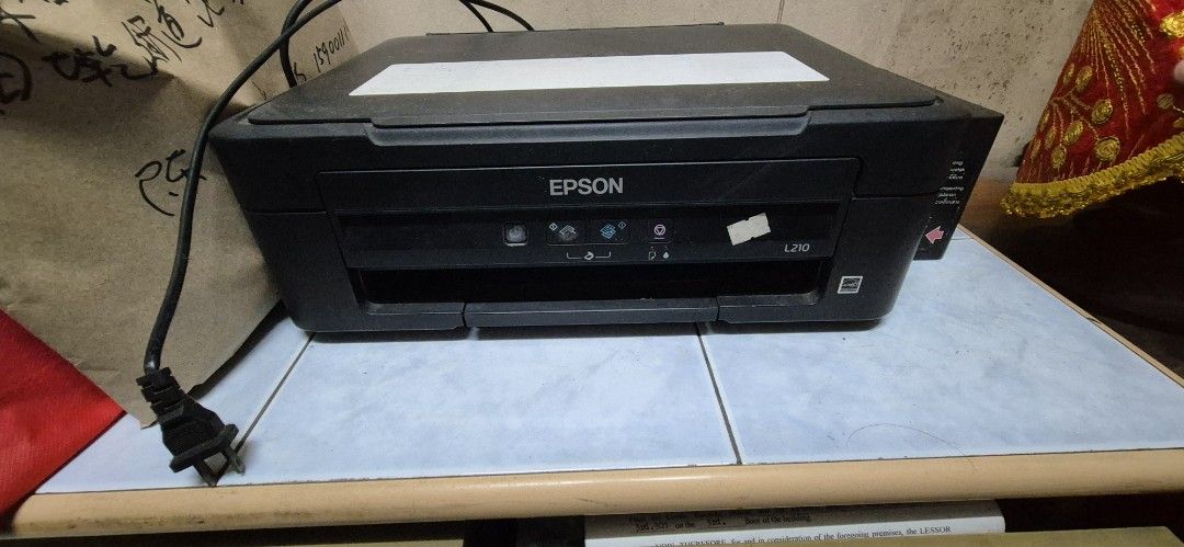 Epson L210 Printer (Category: Printers, Scanners & Copiers) located in Manila. Submitted by book_works (Listing ID 1446215030, Image 2). Description: - Epson L210 Printer - Color: Black - Power cord and usb cord needs replacement - difficult to turn on (damaged power button, possible broken and needs to be repaired) - prints only black and white (problem with printer head) - scanner tray lid hinge broken (easily detaches) RFS: decluttering last u