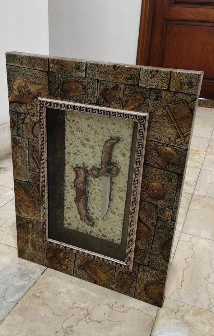 Framed Dagger and Sheath Display (Category: Wall Decor) located in Taguig. Submitted by thrifthub.ph (Listing ID 1446282641, Image 2). Description: Unique wall decor piece. Features a decorative dagger and sheath encased in a textured frame. The frame has a stone-like appearance with embossed details. Great for adding a statement to any room..