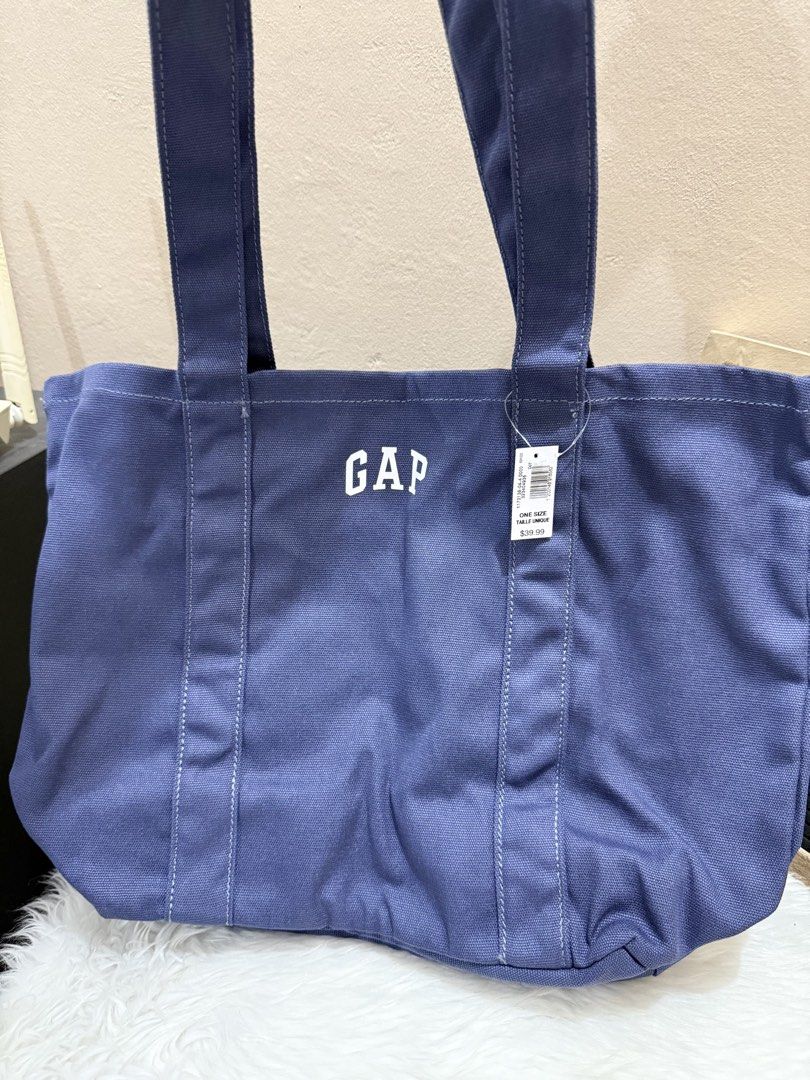 Gap blue canvas tote bag featuring an embroidered logo. (Category: Tote Bags) located in Las Pinas. Submitted by anasonlineshophtplaspinas (Listing ID 1446227429, Image 3). Description: This is a Gap blue canvas tote bag featuring an embroidered logo.Material: It is made from 100% cotton.Price: The tag indicates a price of $39.99.Usage: It is designed for daily utility and is described as spacious..