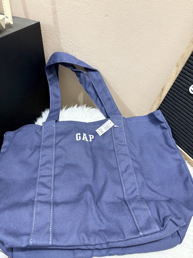 Gap blue canvas tote bag featuring an embroidered logo. (Category: Tote Bags) located in Las Pinas. Submitted by anasonlineshophtplaspinas (Listing ID 1446227429, Image 2). Description: This is a Gap blue canvas tote bag featuring an embroidered logo.Material: It is made from 100% cotton.Price: The tag indicates a price of $39.99.Usage: It is designed for daily utility and is described as spacious..