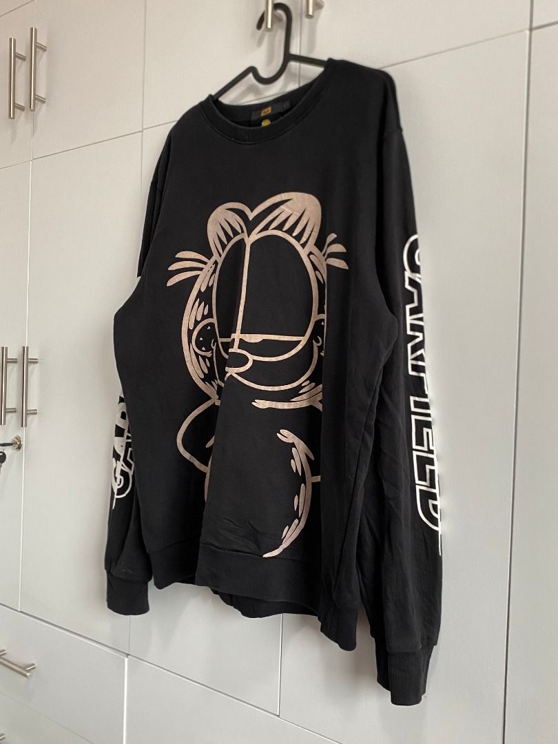 Garfield "by fun" Sweatshirt (Category: Coats, Jackets and Outerwear) located in Tagaytay City. Submitted by grayl_thrift (Listing ID 1446305849, Image 2). Description: - Features a large Garfield graphic on the front - "GARFIELD" text printed vertically on the sleeves - Tagged size XL - Dimes: W23 | L27 | Sleeves 26 - Ideal for any Garfield fan.