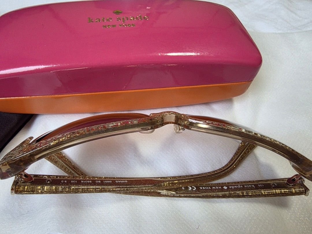Kate Spade New York Sunglasses with Case (Category: Sunglasses & Eyewear) located in Dasmarinas. Submitted by carousel111222 (Listing ID 1446242623, Image 3). Description: - Authentic Kate Spade New York sunglasses - Chic gold glitter frames - Stylish brown gradient lenses - Comes with original pink hard case featuring a cute eye design inside - Includes black cleaning cloth - Ideal accessory for sunny weather.