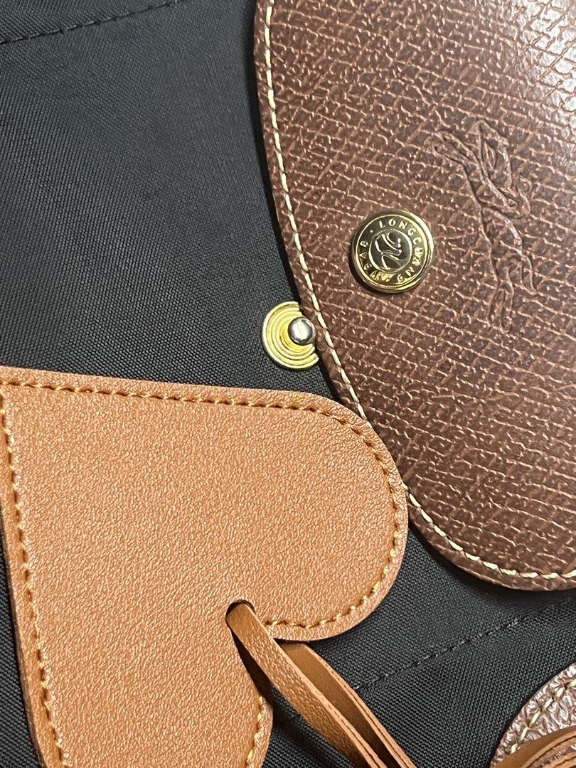 Longchamp Le Pliage Tote medium (Category: Luxury Bags & Wallets) located in Makati City. Submitted by aiahscloset (Listing ID 1446337231, Image 3). Description: - Classic black Longchamp tote bag - Brown leather trim and handles - Adorable heart-shaped leather tag included - Secure zipper closure with snap button flap - Elegant gold hardware details - Ideal for everyday use.