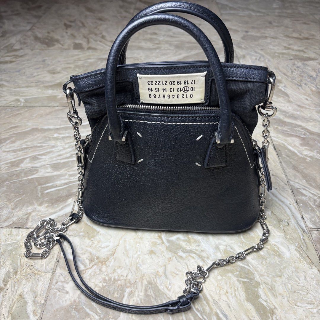 Maison Margiela 5AC Micro bag (Category: Luxury Bags & Wallets) located in Dinalupihan. Submitted by hell.thrift (Listing ID 1446336850, Image 1). Description: This black pebbled calf leather Maison Margiela 5AC Micro bag features the brand’s iconic numerical logo patch and a detachable silver-tone chain strap. -Can be sling bag or hang bag Issue sing of usage not noticeable at the bottom part minimal only 9/10 Condition .