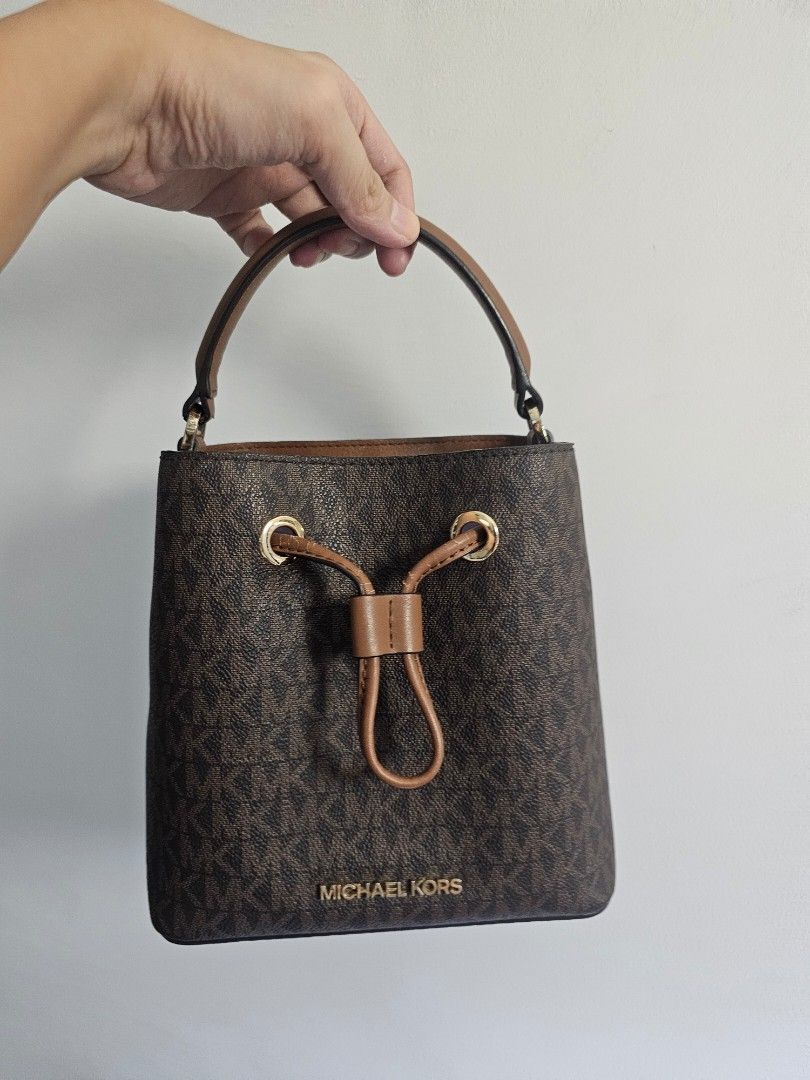 Michael Kors Monogram Bucket Bag (Category: Luxury Bags & Wallets) located in Cavite. Submitted by pink.kai.shop (Listing ID 1446326383, Image 1). Description: - Classic Michael Kors bucket bag - Brown monogram print with leather trim - Secure drawstring closure - Top handle and detachable shoulder strap - Elegant gold hardware details - Ideal for everyday wear With Flaws #sale #bag #michaelkors.
