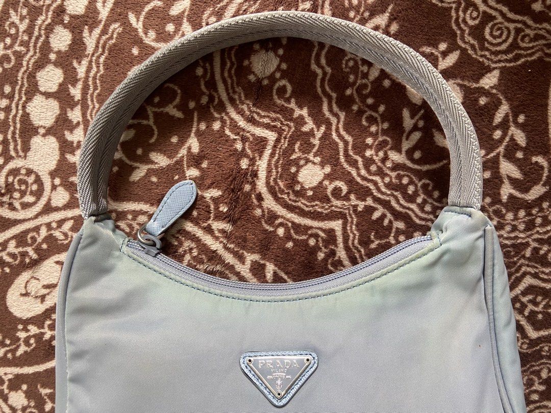 PRADA TESSUTO NYLON MINI Re-Edition 2000 (Category: Luxury Bags & Wallets) located in Pili. Submitted by rgthriftflip29 (Listing ID 1446177992, Image 3). Description: - Authentic / Not Guaranteed -Prada shoulder bag - Made in Italy - Light blue nylon material - Silver hardware - Zipper closure - COMPLETE Interior Prada Milano tag - Ideal for everyday use, fits essentials, and elegance L: 9” W: 3” D: 5” Handle: 7” ❌ISSUE: MISSING CLOCHETTE x MILD 