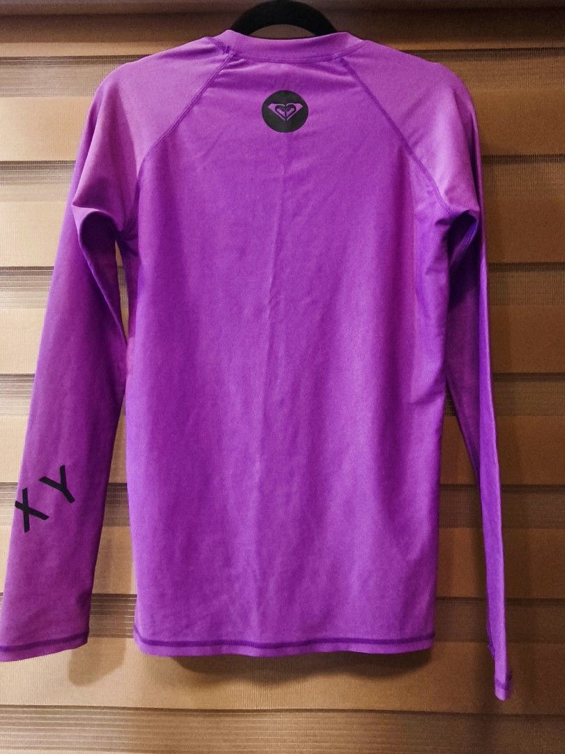 Roxy Purple Long Sleeve Rash Guard Top (Category: Rash guard) located in Baguio. Submitted by zia_zab (Listing ID 1446309041, Image 2). Description: - Purple Roxy long sleeve rash guard - Features Roxy logo on front and sleeve - Made from a comfortable nylon and spandex blend - Ideal for surfing, swimming, or any water activity - Provides a comfortable fit for active days - Refer to label for care instructions -In very good condition -No flaws -C