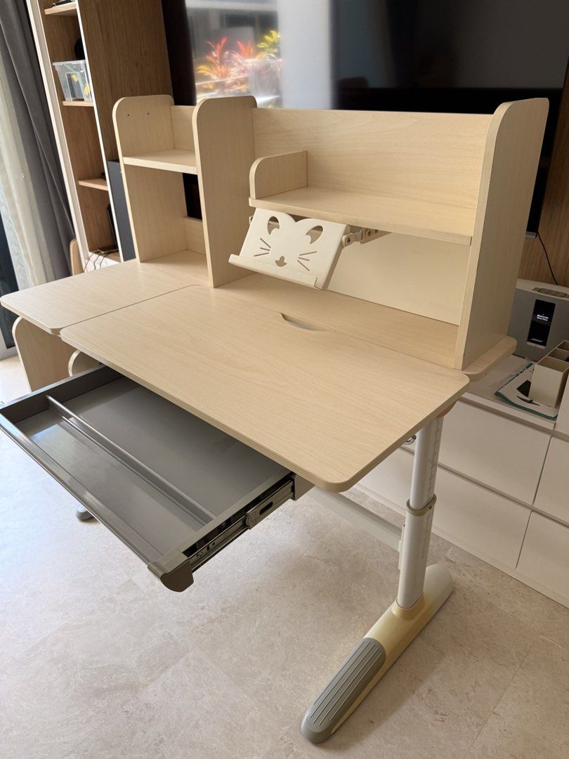 Study Table - Adjustable (Category: Tables & Sets) located in Singapore. Submitted by first.serve.in (Listing ID 1446226033, Image 2). Description: - Adjustable height study table - Light wood finish - Table top angle adjustable for project work - Features overhead shelves for storage - Includes a pull-out drawer.