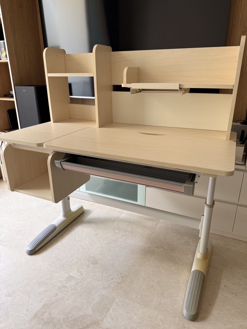 Study Table - Adjustable (Category: Tables & Sets) located in Singapore. Submitted by first.serve.in (Listing ID 1446226033, Image 1). Description: - Adjustable height study table - Light wood finish - Table top angle adjustable for project work - Features overhead shelves for storage - Includes a pull-out drawer.