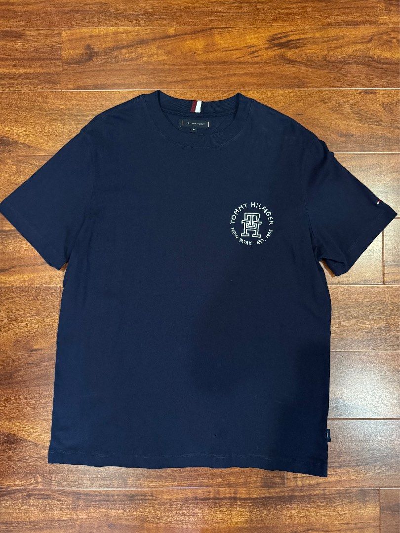 Tommy Hilfiger Navy Blue T-Shirt with Logo (Category: Tshirts & Polo Shirts) located in Kuala Lumpur. Submitted by 4rty9ne (Listing ID 1446177110, Image 2). Description: - Navy blue Tommy Hilfiger t-shirt - Size M. Pit 22 L 28 - Features classic circular logo with 'Tommy Hilfiger New York Est. 1985' text - Short sleeves - Made from comfortable cotton material - Ideal for casual everyday wear.